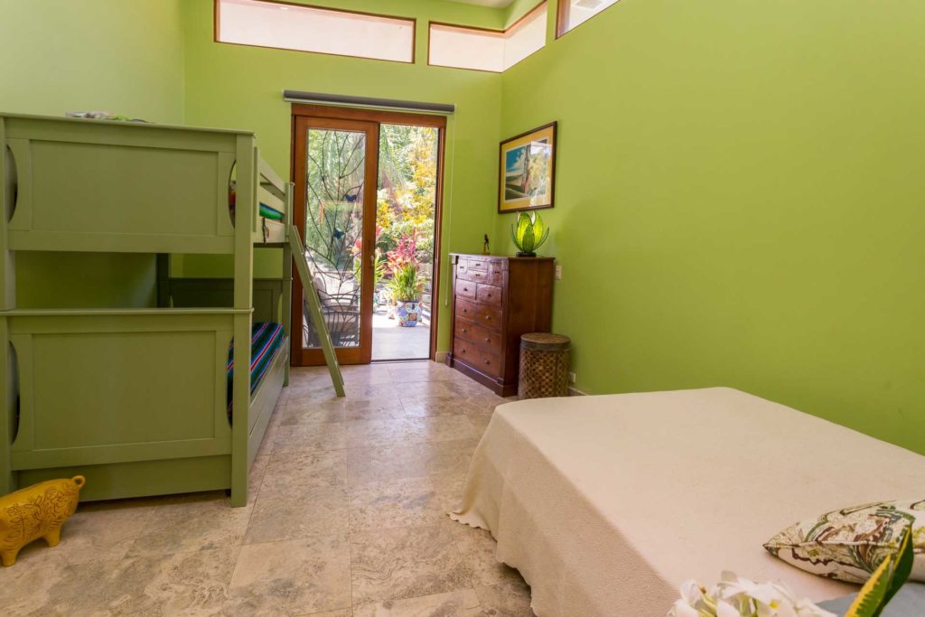 The beautiful rainforest bedroom features a full bed, a deluxe bunk bed set, and a private patio just outside.