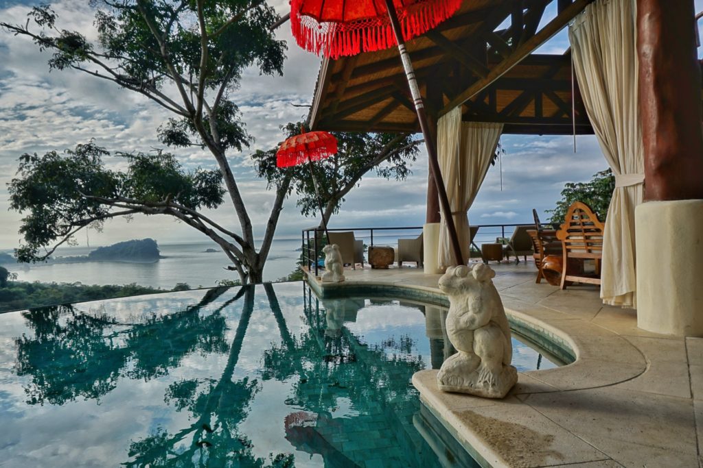 The infinity pool has a luxurious design with umbrellas set in hand-carved statues. The ocean view is breathtaking.