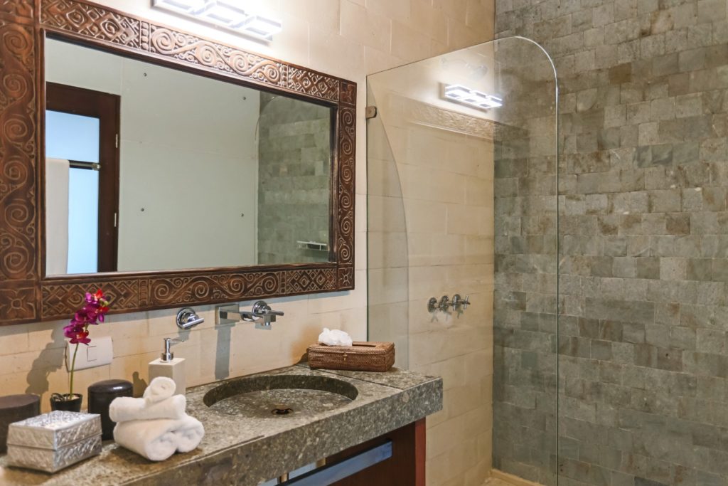 This bathroom features a granite counter and sink and a stunning mirror with a hand-carved frame.