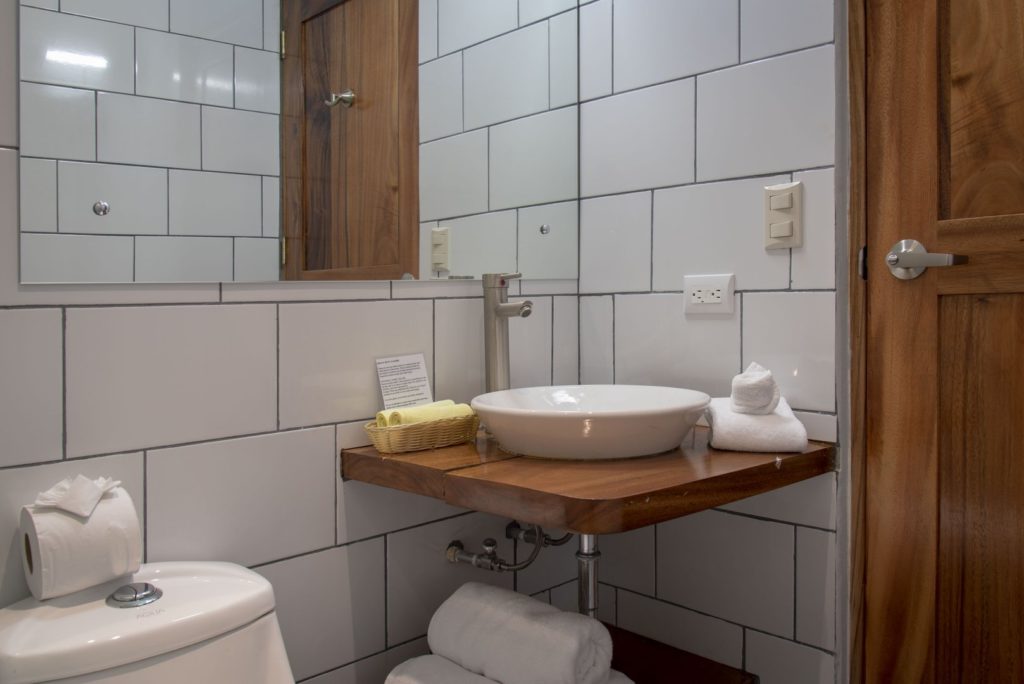 This bathroom is tastefully tiled from the floor to the ceiling and has a large mirror.