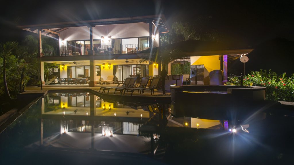 An amazing villa in the popular vacation spot of Playa Flamingo is reflected off the private infinity pool at night.