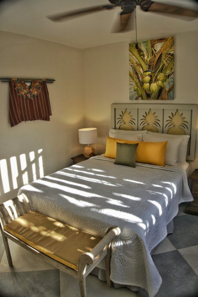 The guest bedroom has some beautiful artwork and a pineapple-inspired headboard.