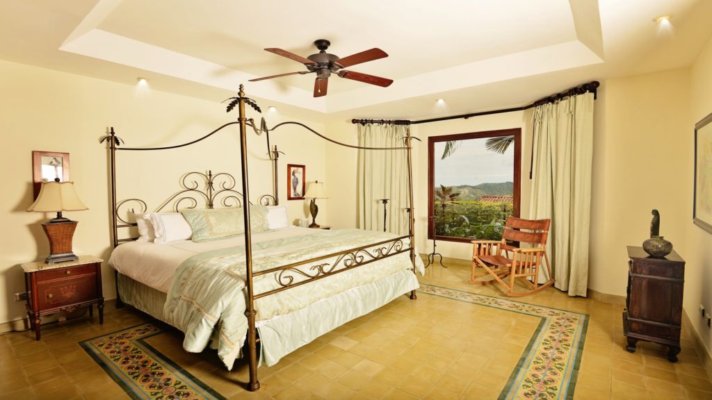 Elegantly furnished, this bedroom offers a splendid view of lush greenery.