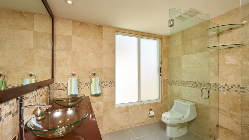 This extra large bathroom has floor to ceiling tiles and beautiful glass shower.