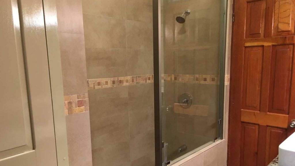 A large clean shower with tile from floor to ceiling and glass doors.