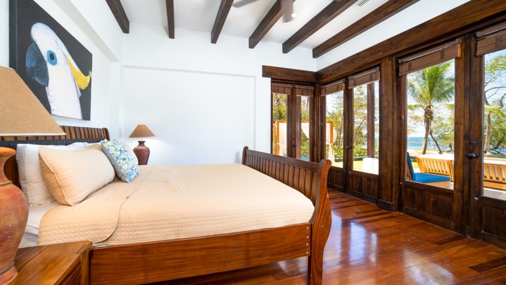 A master bedroom with all amenities imaginable featuring tall ceilings with exposed wood beams.