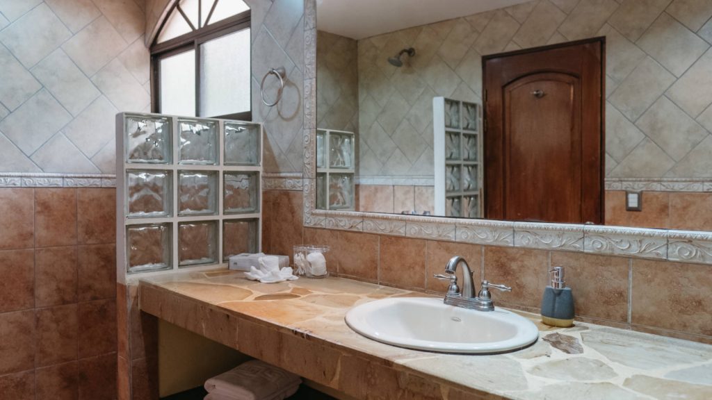 A bathroom on the upper level with a beautiful stone counter and a large shower.