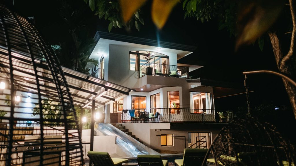 The villa and two-level pool with slide beautifully light up the night.