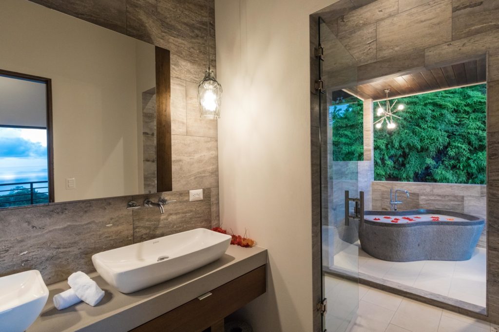 The bright and modern master bathroom features a gorgeous natural stone tub.