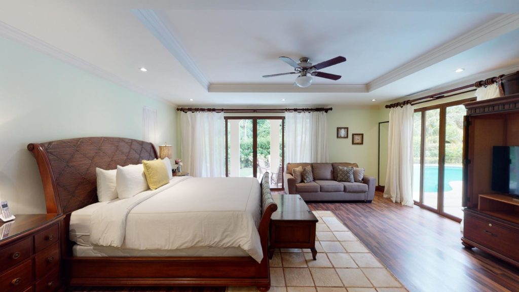 Crafted with exquisite woodwork, this bedroom is a haven of refined elegance. 
Featuring a comfortable sitting area and direct access to the pool and stunning gardens, it's a dreamy escape.