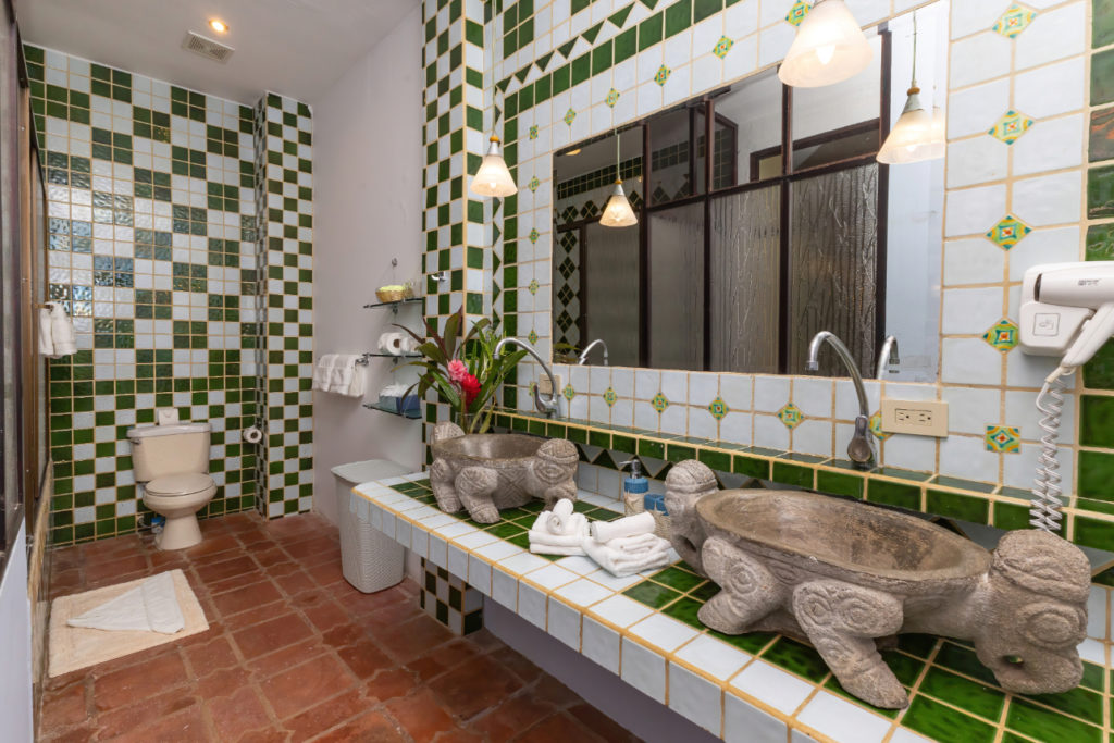 The bathroom features a unique design with ceramic tiled countertops and a hand-carved stone lavatory