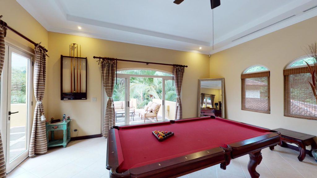 The games room has a pool table and is adorned with exquisite decor, with a terrace and lush jungle vista.
