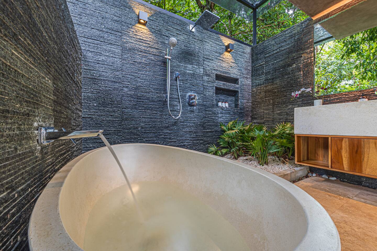 Stone soaking bathtub in an open-air bathroom with jungle surroundings near Dominical, Costa Rica.