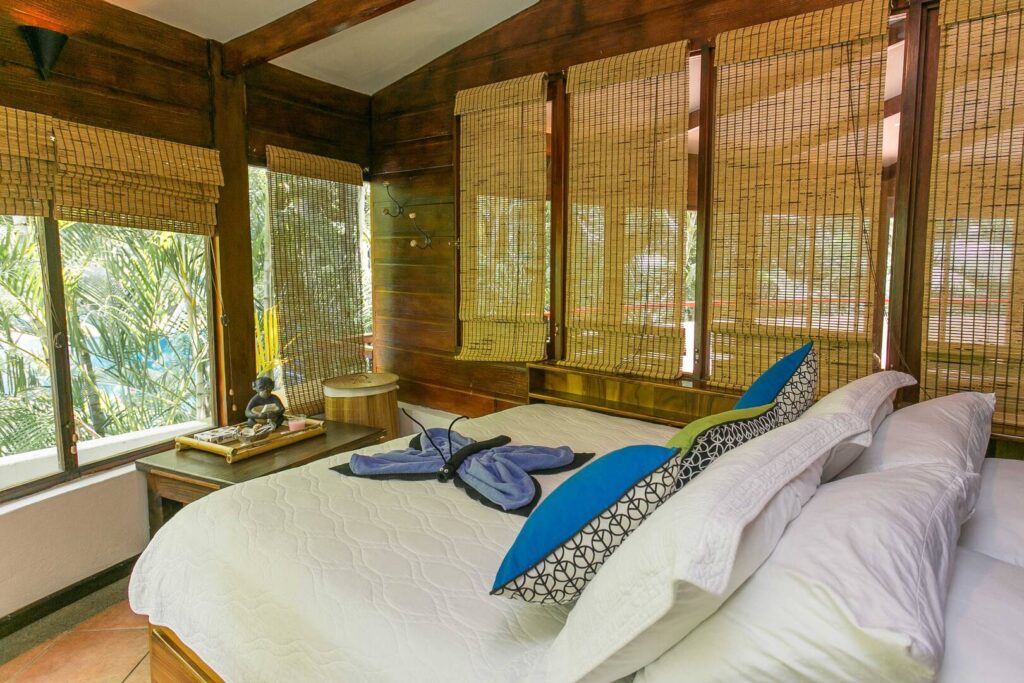 This bedroom is decorated with wood and woven blinds for a natural tropical cabin vibe.