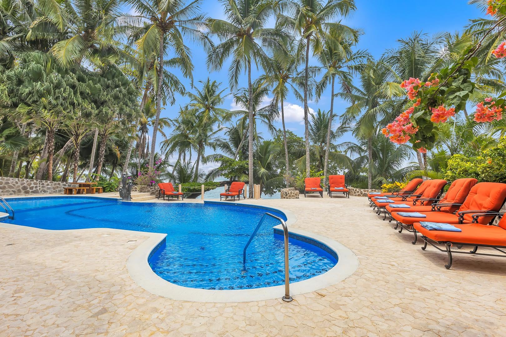 Resort-style swimming pool with sun loungers at a luxury beachfront vacation villa in Playa Tambor, Costa Rica.