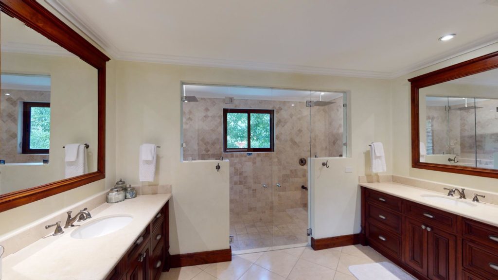 In this expansive and refined bathroom, you'll find ample washbasins and a generously sized shower area for your convenience.