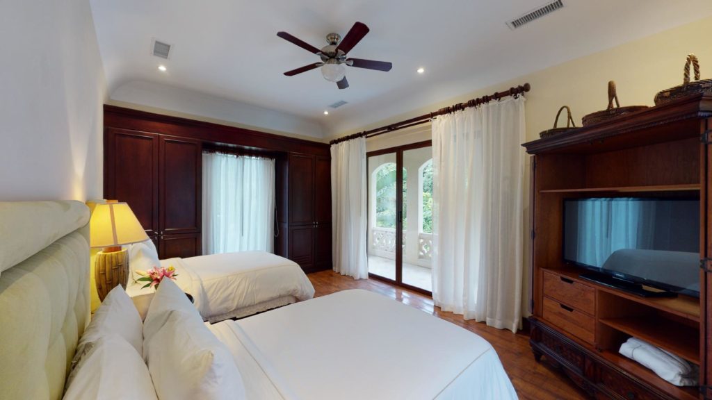 Second bedroom upstairs with two full beds offers access to the terrace with vistas of a serene, exotic forest.