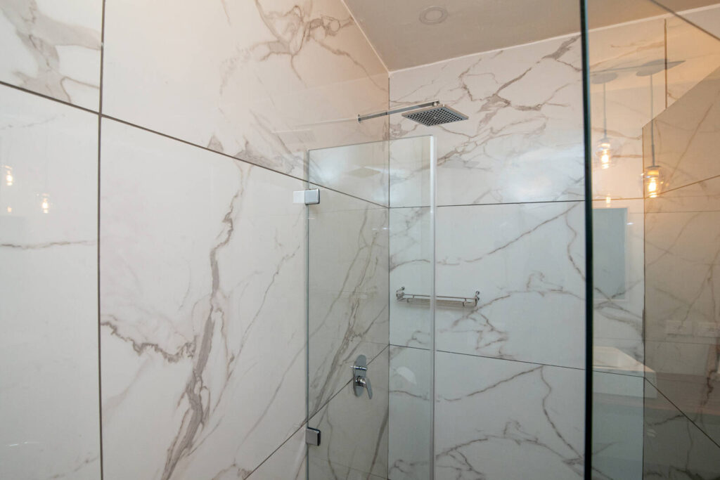 freshen up in style in this luxury rain shower with glass doors and beautiful porcelain tiles.