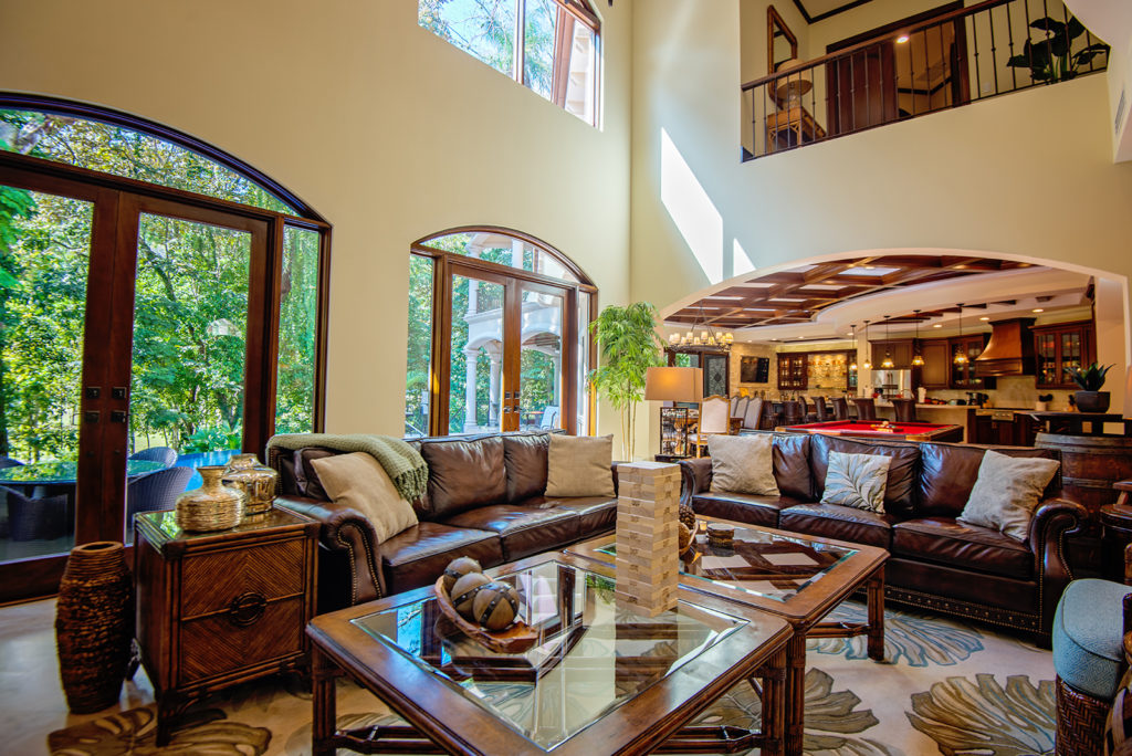 Elegance meets exotic allure in our living room, with its beautiful high ceilings and furniture crafted from exotic wood. The adjacent view of the pool and lush gardens brings a sense of calm to this refined space.