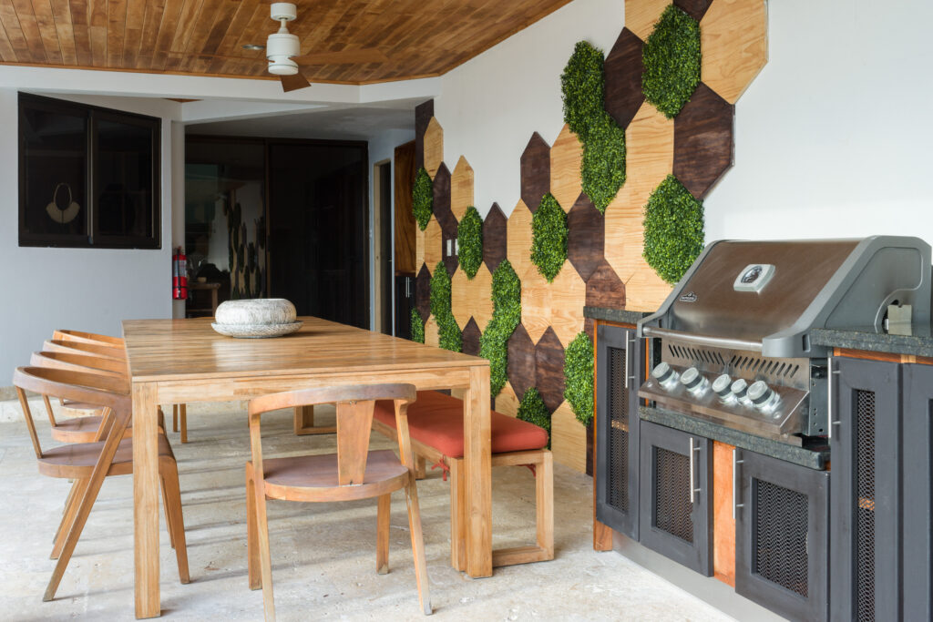 A stylish outdoor dining area with natural wood textures, geometric greenery, and a built-in grill—perfect for relaxed meals in the fresh Manuel Antonio air.