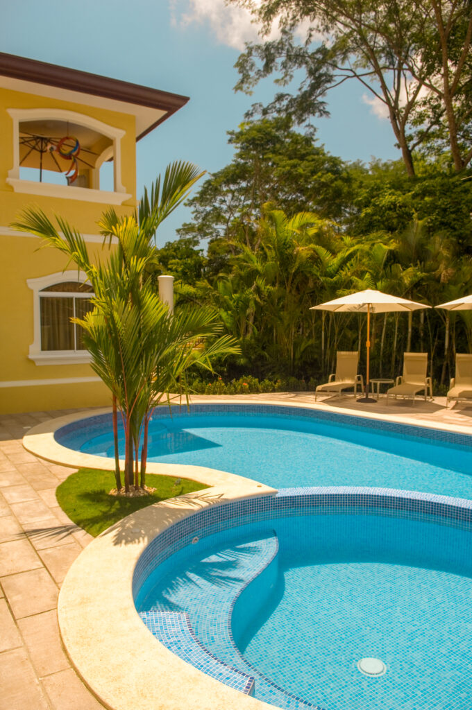 The curved pool and jacuzzi are framed by tropical gardens and shaded loungers on the villa’s private terrace.