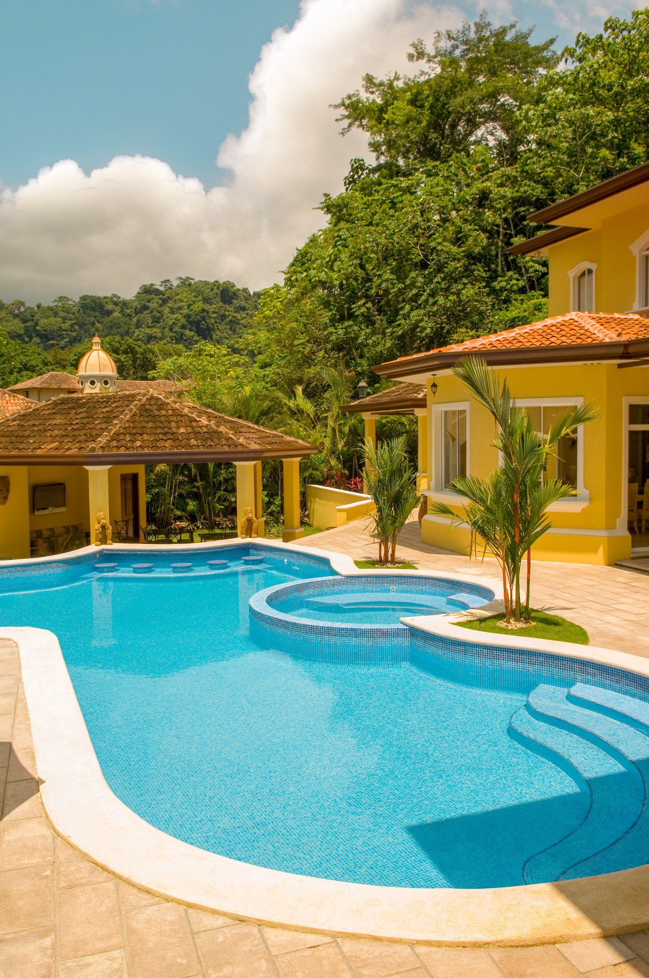 Private swimming pool with round jacuzzi and swim-up bar facing a covered pool house at a Los Sueños villa in Jacó Costa Rica.