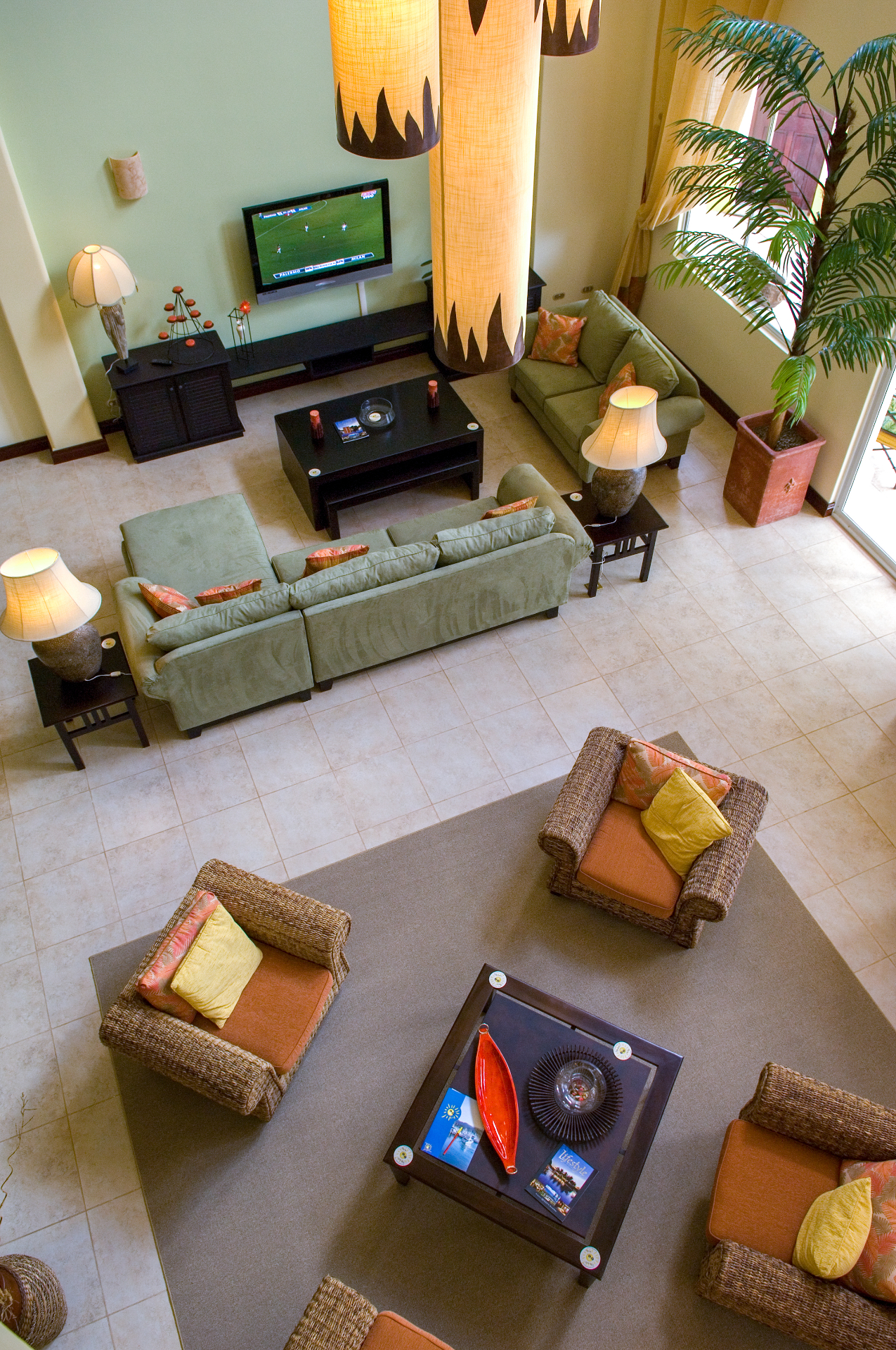 Overhead view of great room lounge with sofas, wicker chairs, coffee table, and large pendant lights inside a Los Sueños villa.