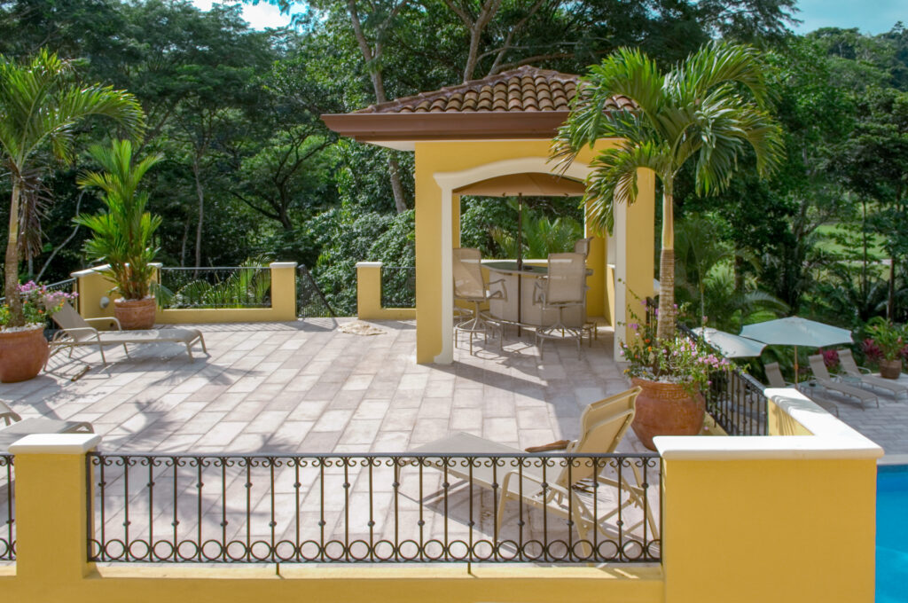 An elevated terrace with loungers and a covered gazebo overlooking tropical greenery.