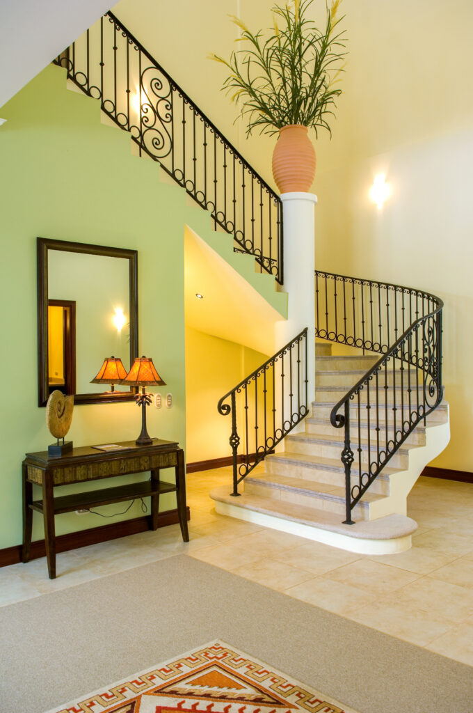A graceful curved staircase with wrought-iron railings creates an elegant entrance within the villa.