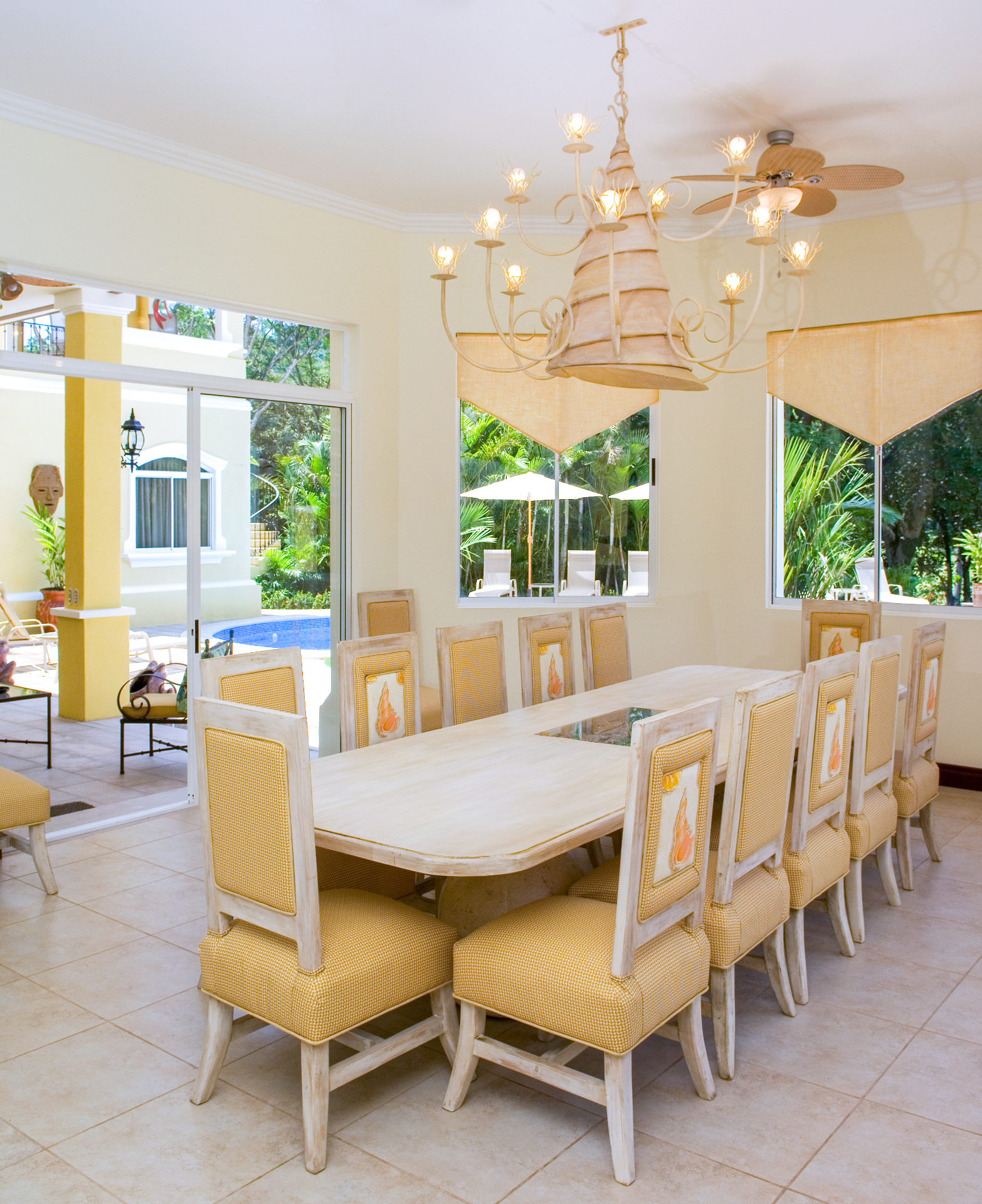 Large dining table with fourteen chairs beside sliding doors opening to the pool terrace at a Los Sueños villa in Jacó Costa Rica.
