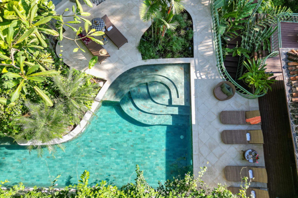 A newly renovated pool and lounge area, surrounded by lush tropical gardens.
