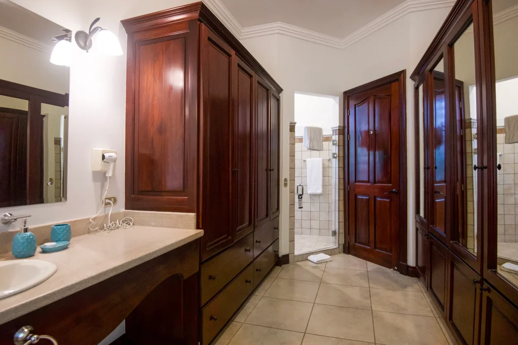 A spacious ensuite bathroom with custom wood cabinetry, double vanity space, and a walk-in shower beyond.