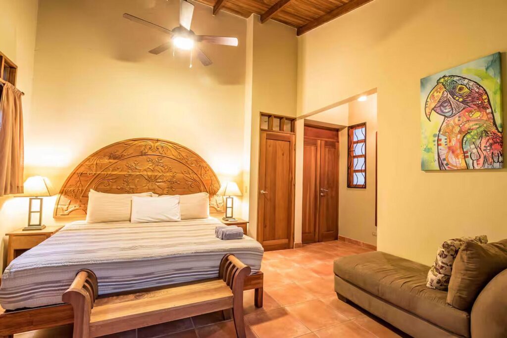 This bedroom has a beautiful hand-carved headboard and colorful fine art. 