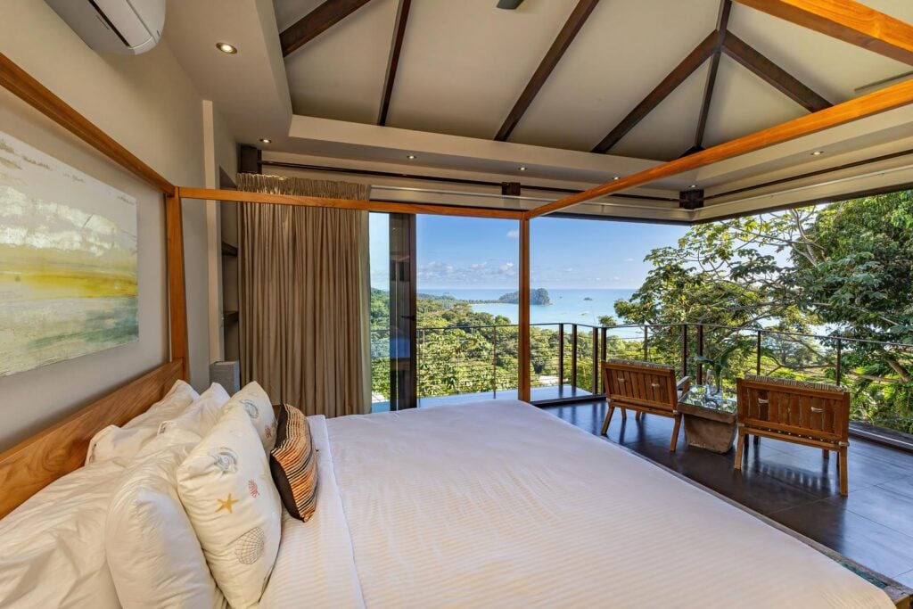Gentle natural light fills this peaceful bedroom, where sliding doors open to views of the surrounding jungle and the Pacific Ocean.