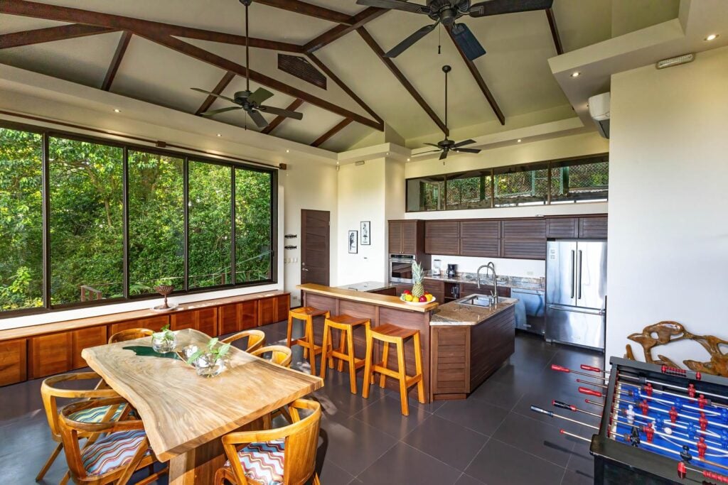A spacious open-concept kitchen and dining area surrounded by jungle views, creating a comfortable setting for shared meals and time together.