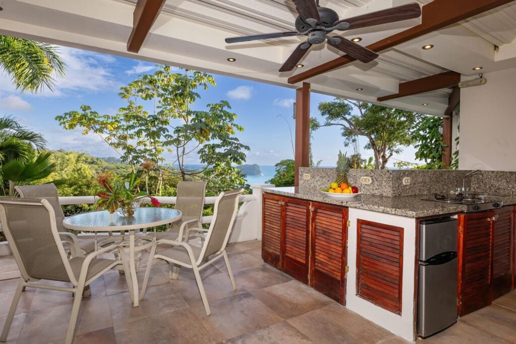 The covered terrace connected to the twin bedroom opens to an outdoor kitchen and dining area, offering spectacular ocean views and a beautiful tropical setting for open-air meals.