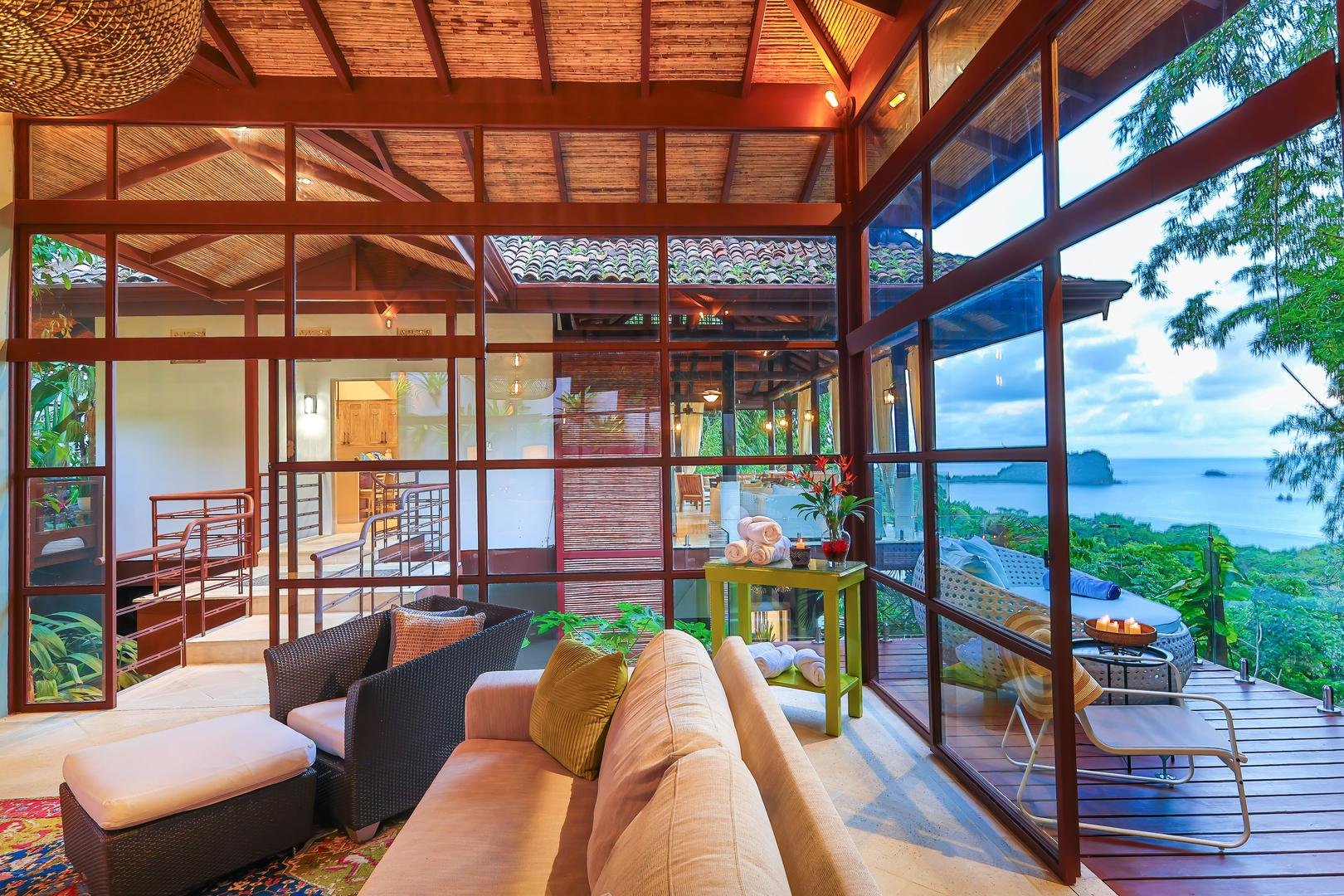 Glass-walled living room with seating and ocean view in the new wing of Casa Vista Azul