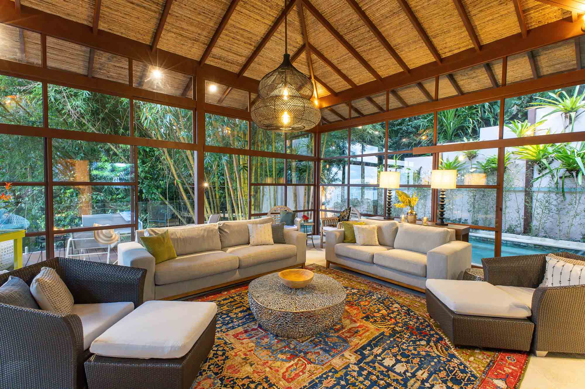 Interior lounge of the new wing with floor-to-ceiling glass, seating area, natural textures, filtered light, and jungle surroundings at a villa in Manuel Antonio, Costa Rica.