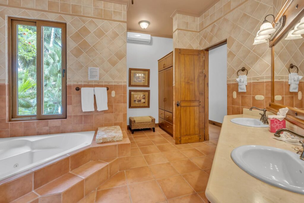 This bright, spa-like bathroom features warm tiles, plenty of space, and a cozy corner tub made for pure comfort.