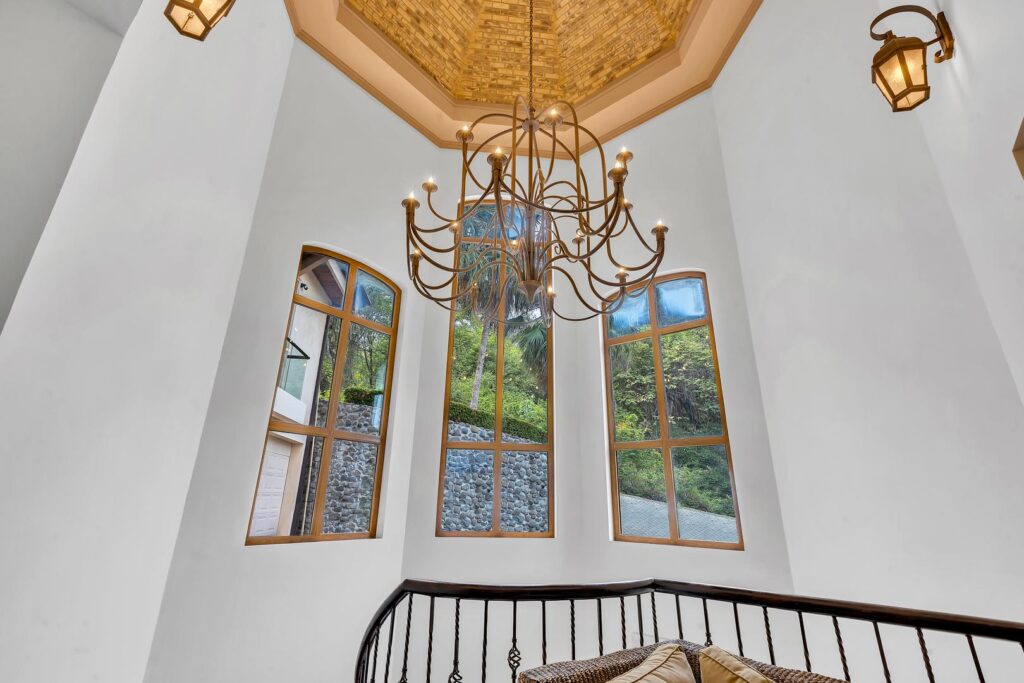 Golden light pours through tall windows, highlighting the dramatic chandelier above.