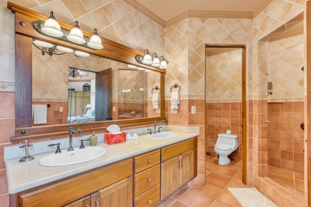 A well-appointed bathroom with double sinks, warm tiles, and a roomy shower—perfect for comfort and convenience.