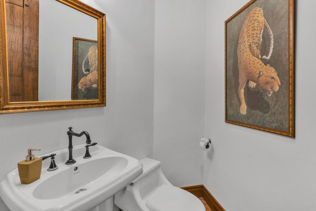 A bright, neatly designed half-bath with classic touches and tropical artwork.