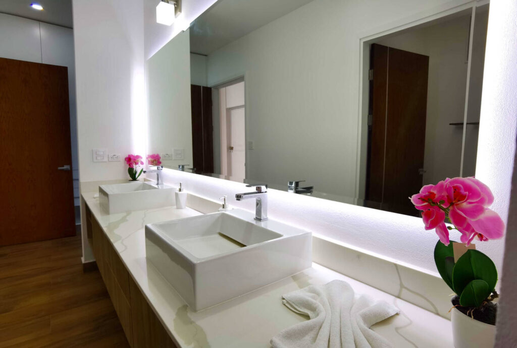 This bathroom features a double sink and huge mirror. The villa is furnished with the best modern items.