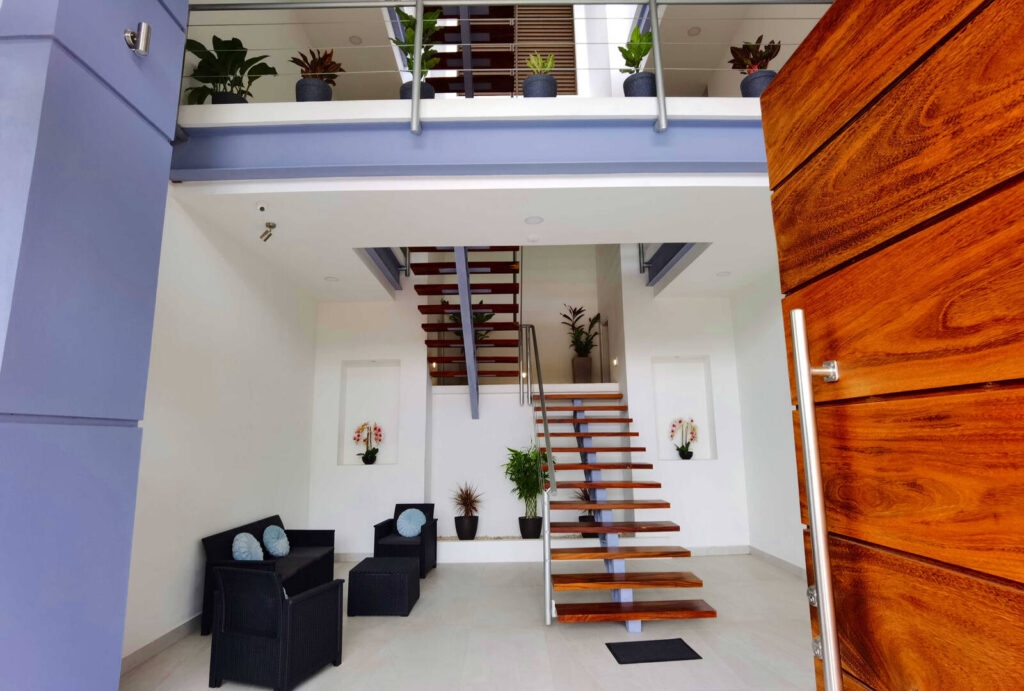 The three floors of this minimalistic house are reached via the beautiful wooden stairs adorned with tropical plants.