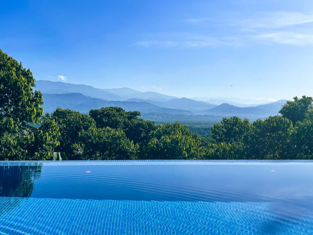 Your private infinity pool is framed by lush canopy and distant mountains.