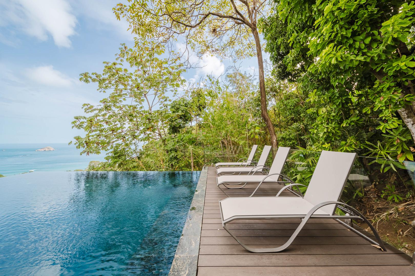 Infinity pool with lounge chairs overlooking jungle and ocean in Manuel Antonio Costa Rica