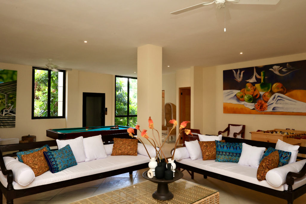 A beautifully appointed game room lounge area, bathed in natural light and overlooking lush exotic gardens.