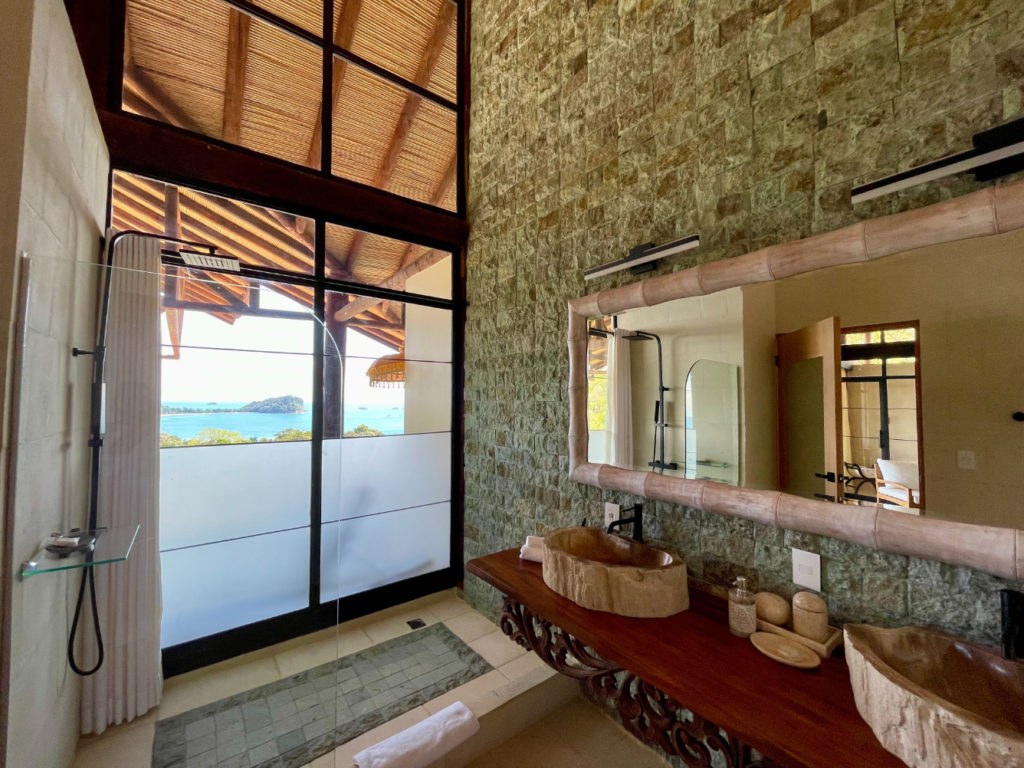 A uniquely exceptional bathroom boasting remarkable design features. Towering glass windows offer breathtaking ocean vistas.