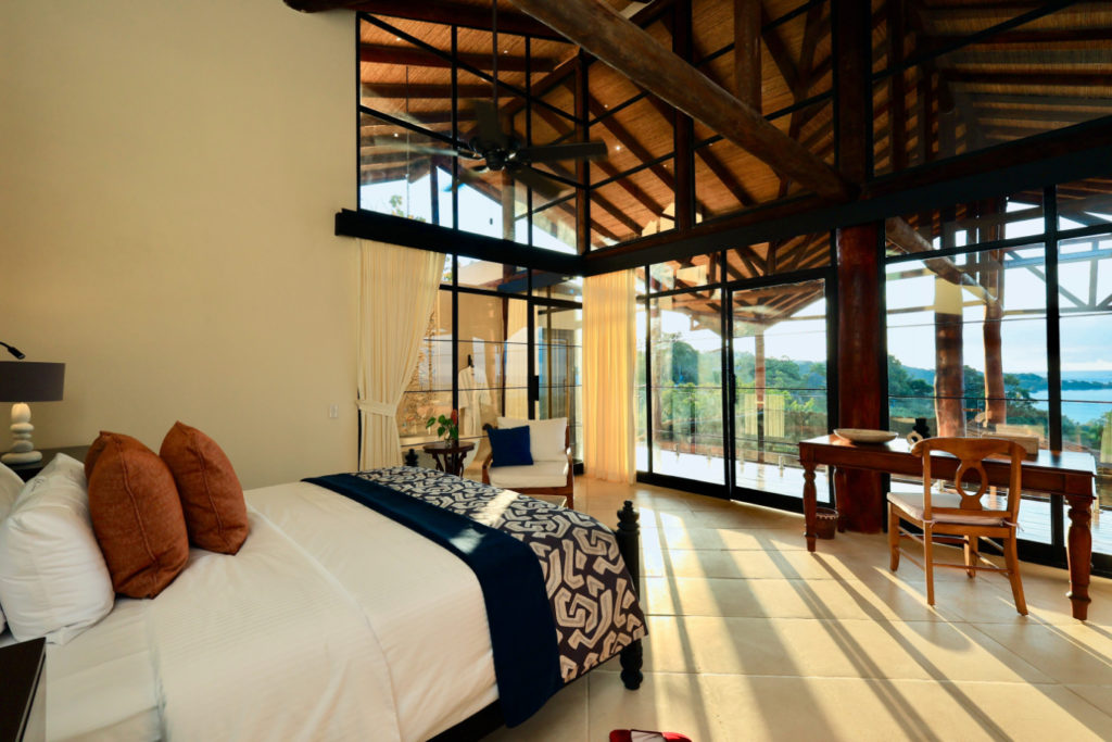 The master suite boasts ingeniously crafted lofty ceilings with a breathtaking natural wood framework, and tall glass doors offer sublime views of Manuel Antonio National Park.