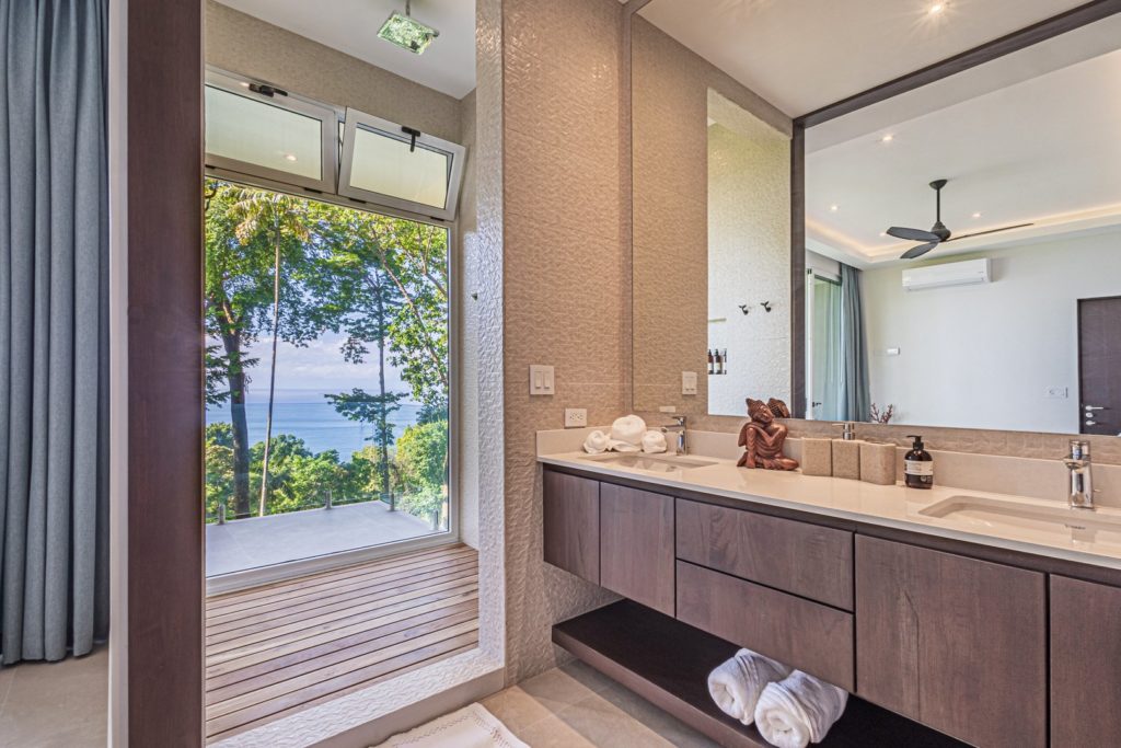 The spacious rain shower in this luxury ensuite bathroom boasts a stunning floor-to-ceiling ocean view.